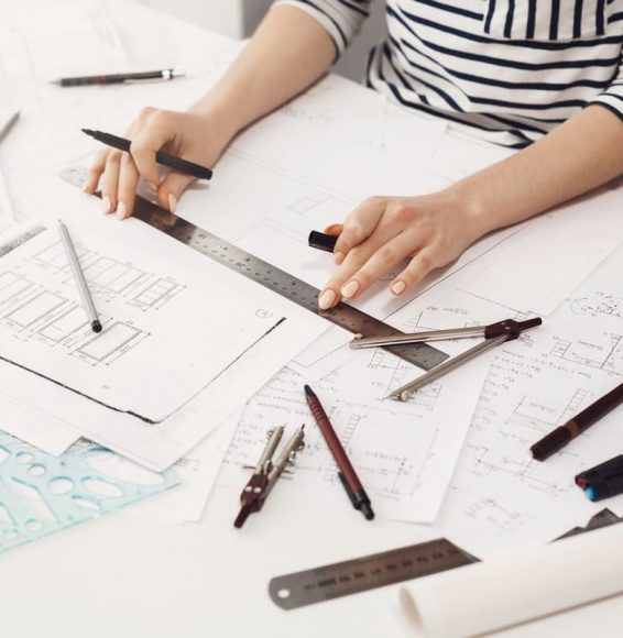 Close up detail of young professional female engineer hands making edits with ruler and liner in new team project. Teamwork and business